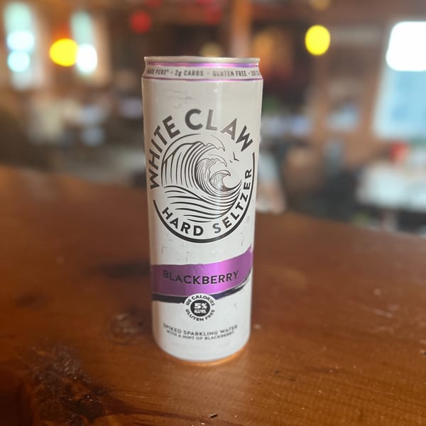 A White Claw Blackberry Hard Seltzer can sits on a wooden bar top at Riley's Place.