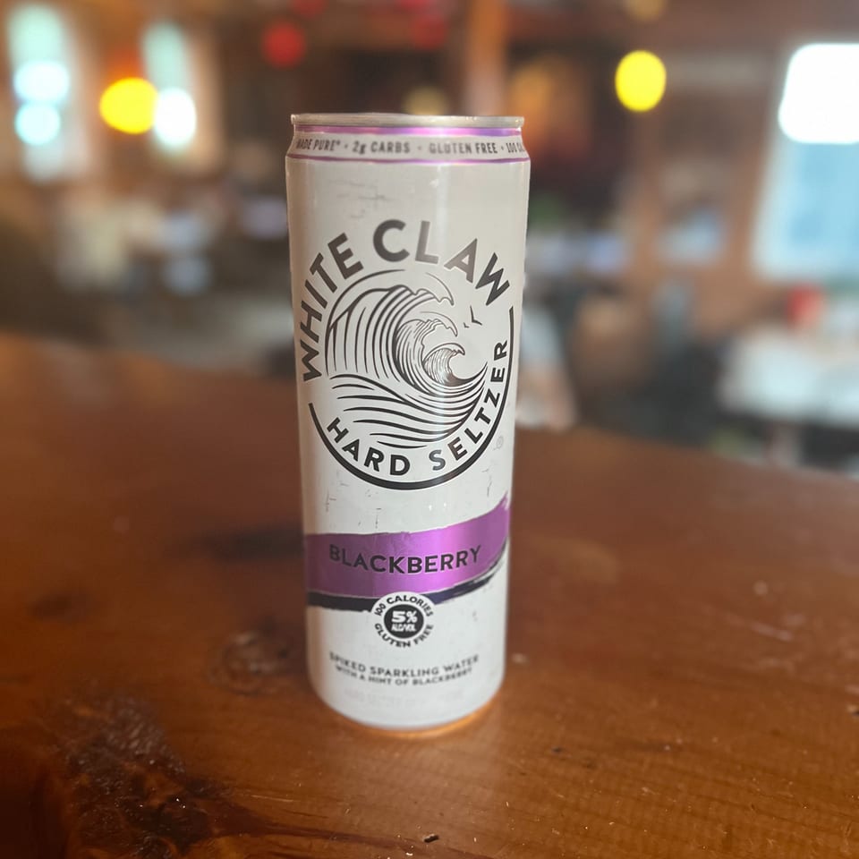 A White Claw Blackberry Hard Seltzer can sits on a wooden bar top at Riley's Place.