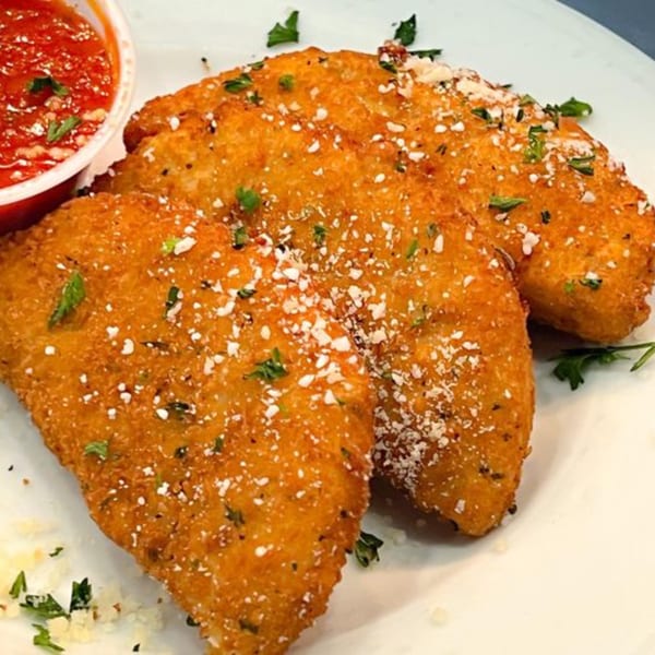 Three golden-brown fried mozzarella sticks, sprinkled with parmesan and parsley, served with marinara sauce.