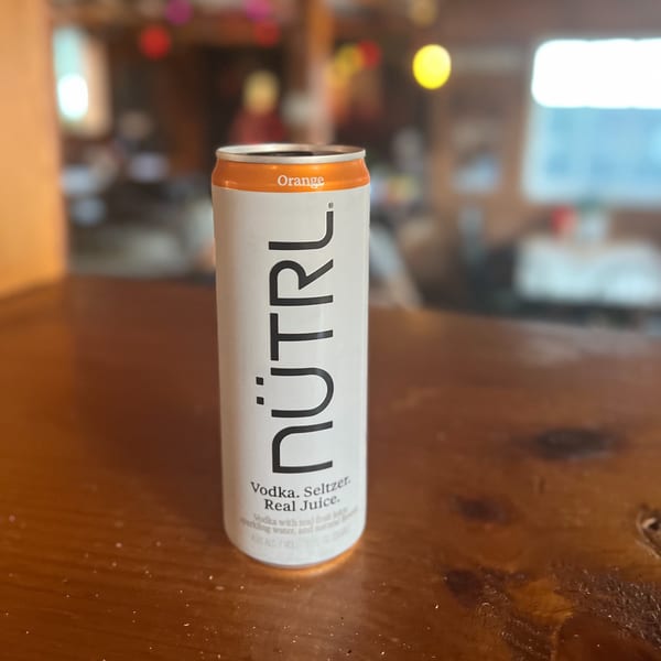 A can of NÜTRL Orange vodka seltzer on a wooden table at Riley's Place.
