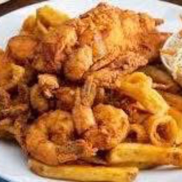 A platter of golden-fried shrimp, fish, and calamari with french fries and coleslaw.