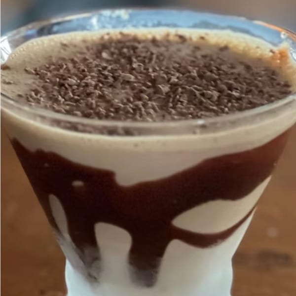 A chocolate martini with chocolate syrup drizzled inside the glass and chocolate shavings on top.
