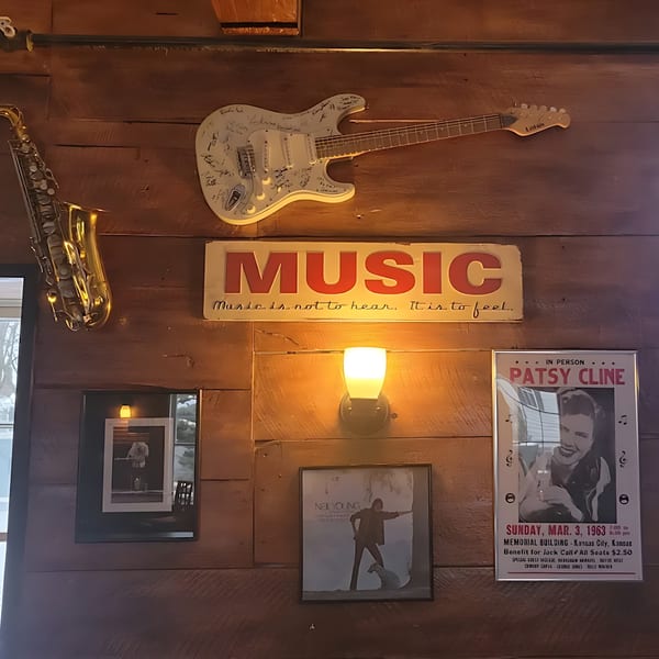 A wooden wall adorned with a signed white guitar, a saxophone, and music-themed posters.