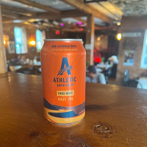 An orange Athletic Brewing Co. Free Wave Hazy IPA can sits on a wooden bar at Riley's Place.