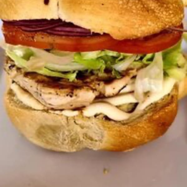 Grilled chicken sandwich on a bun with lettuce, tomato, red onion, and mayonnaise.